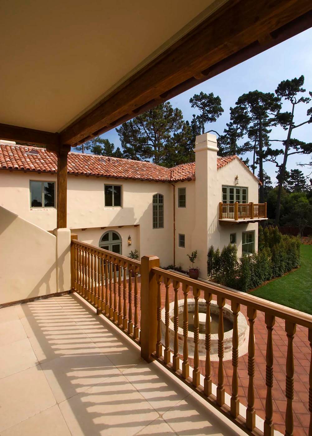 Exterior of a SPANISH STYLE CALIFORNIA LUXURY HOME with large red tiled PATIO as seen from upstairs deck. Architecture photography by Eagle Visions Photography