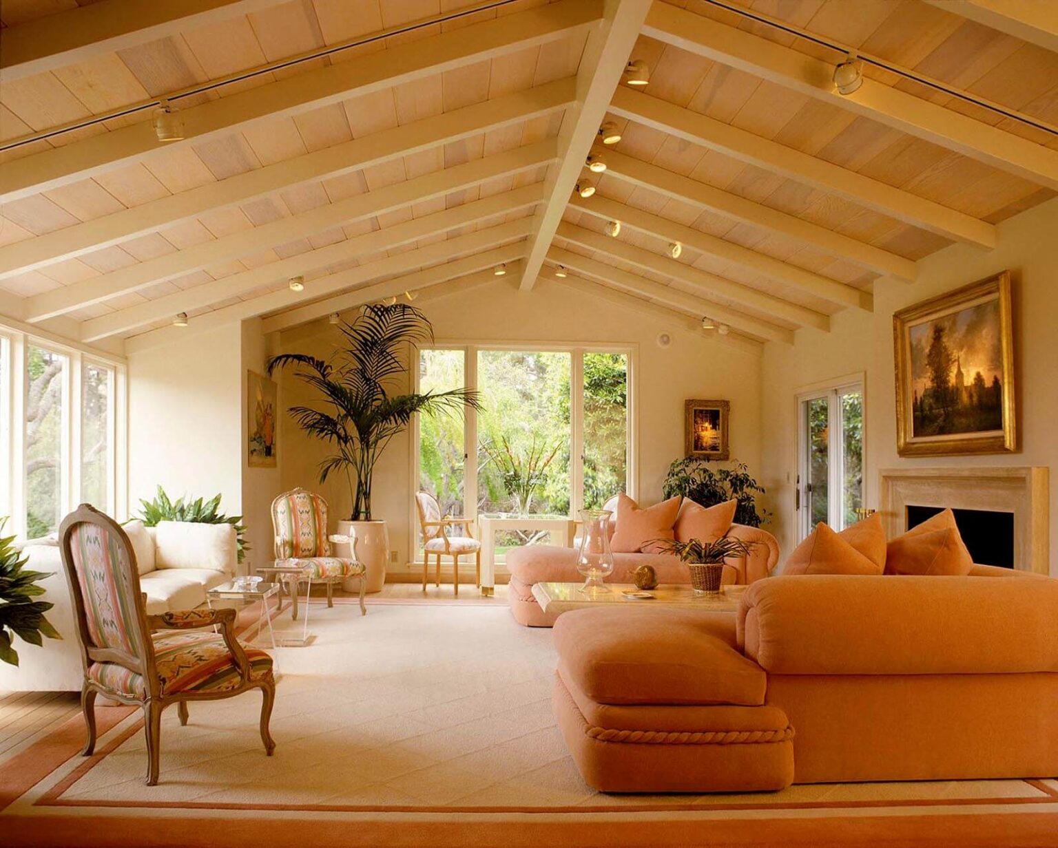 A LIVING ROOM with classical paintings, open beam ceiling, overstuffed peach colored couches and lots of natural light.- Architecture photography by Eagle Visions Photography