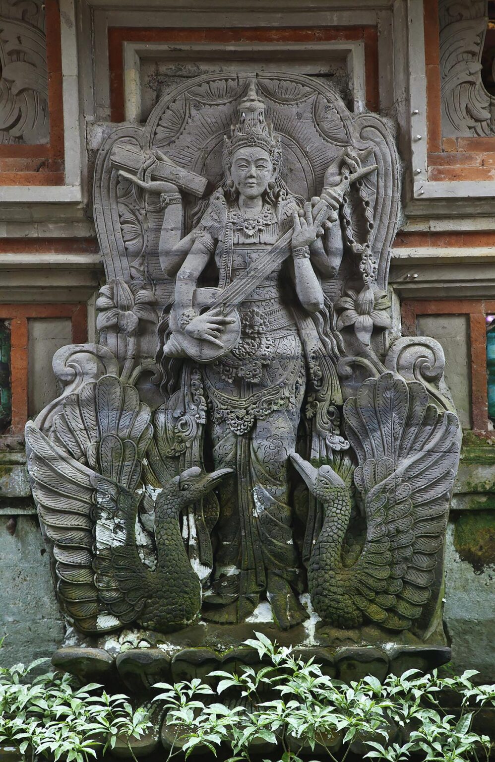 A stone carving of SARASWATI, the goddess of knowledge, music and the arts at the entrance of PURA DESA - UBUD, BALI, INDONESIA