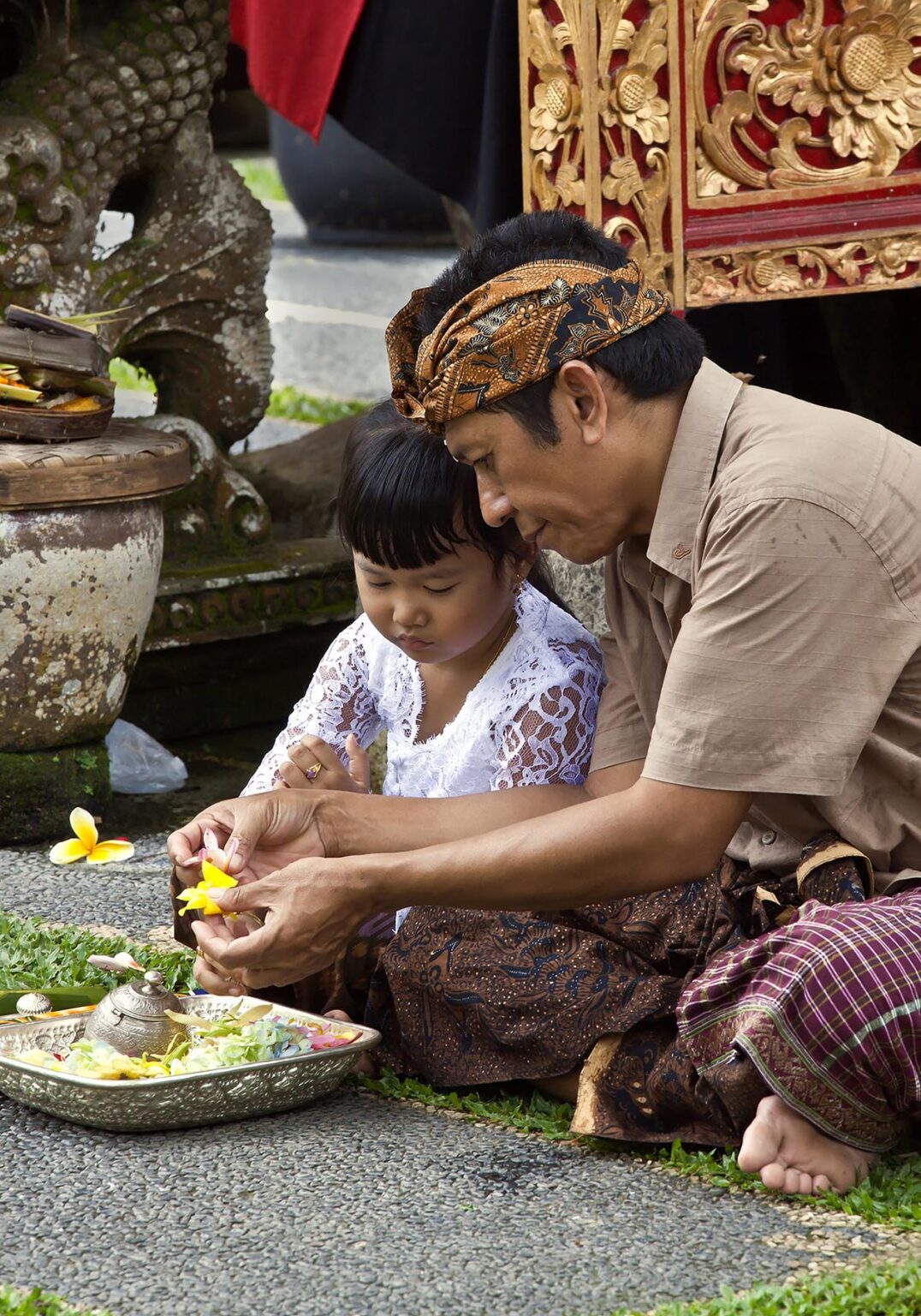 Father and daughter make puja at PURA TAMAN SARASWATI during the GALUNGAN FESTIVAL - UBUD, BALI, INDONESIA