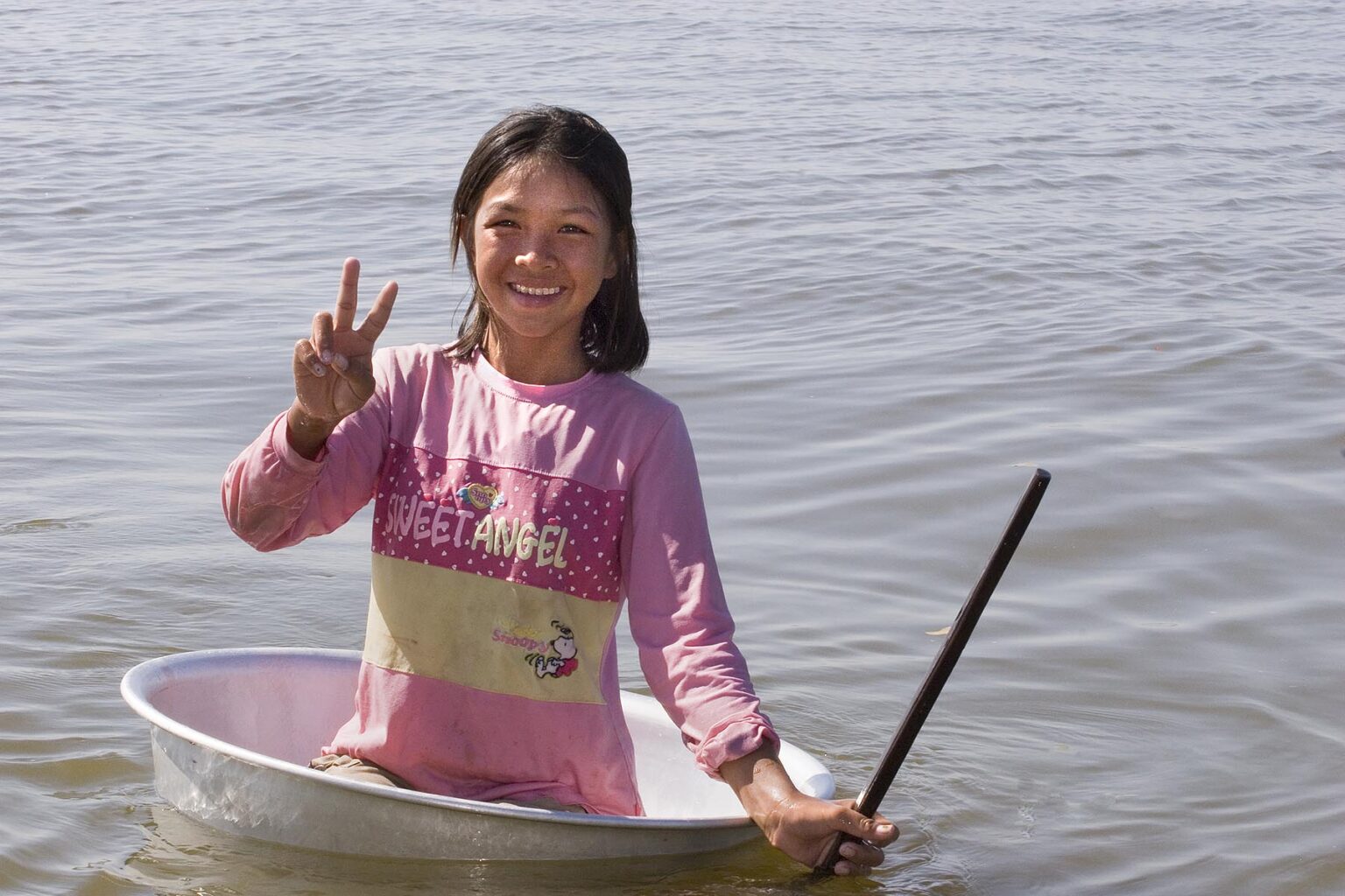 Young girl in a tub from the Vietnamese floating village of Chong Kneas plays in lake Tonle Sap - Siem Reap, Cambodia