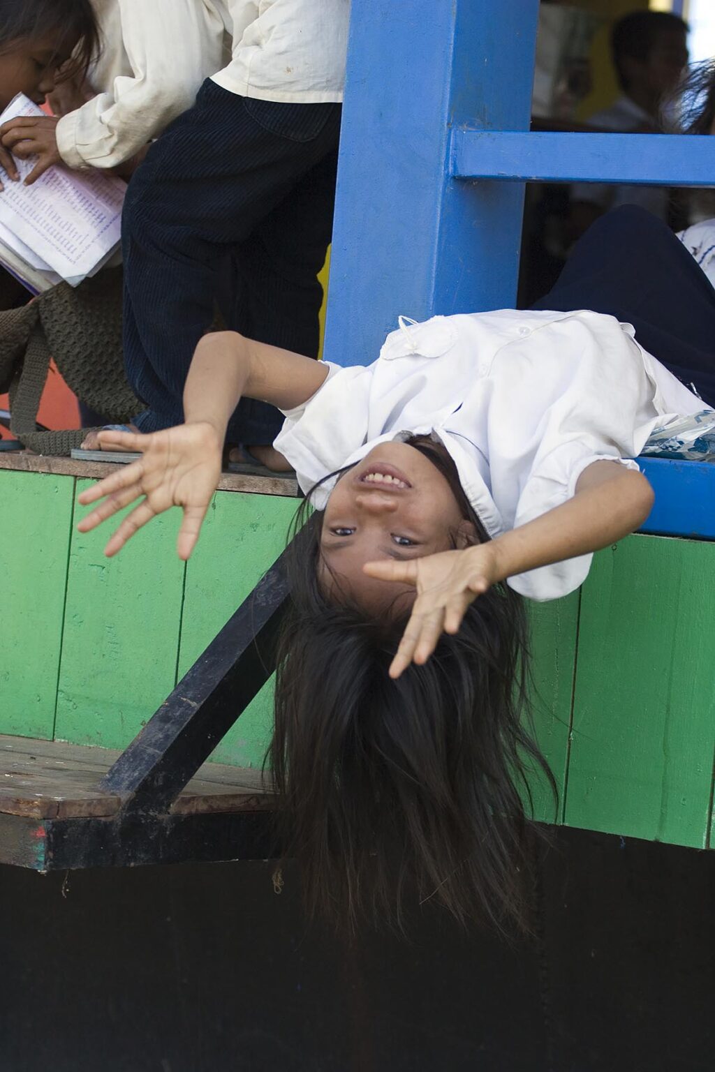 Schoolgirl plays upside down in the Vietnamese floating village of Chong Kneas on lake Tonle Sap - Siem Reap, Cambodia