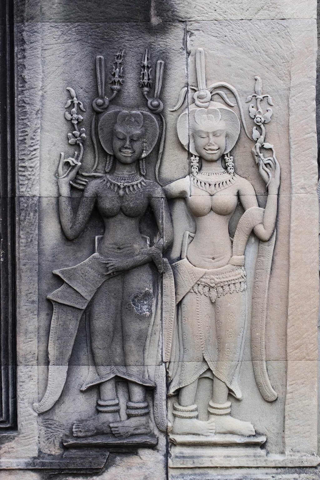 Stone carved bas relief of two smiling Apsaras (celestial maidens) at Angkor Wat, built in the 11th century by Suryavarman the 2nd - Cambodia