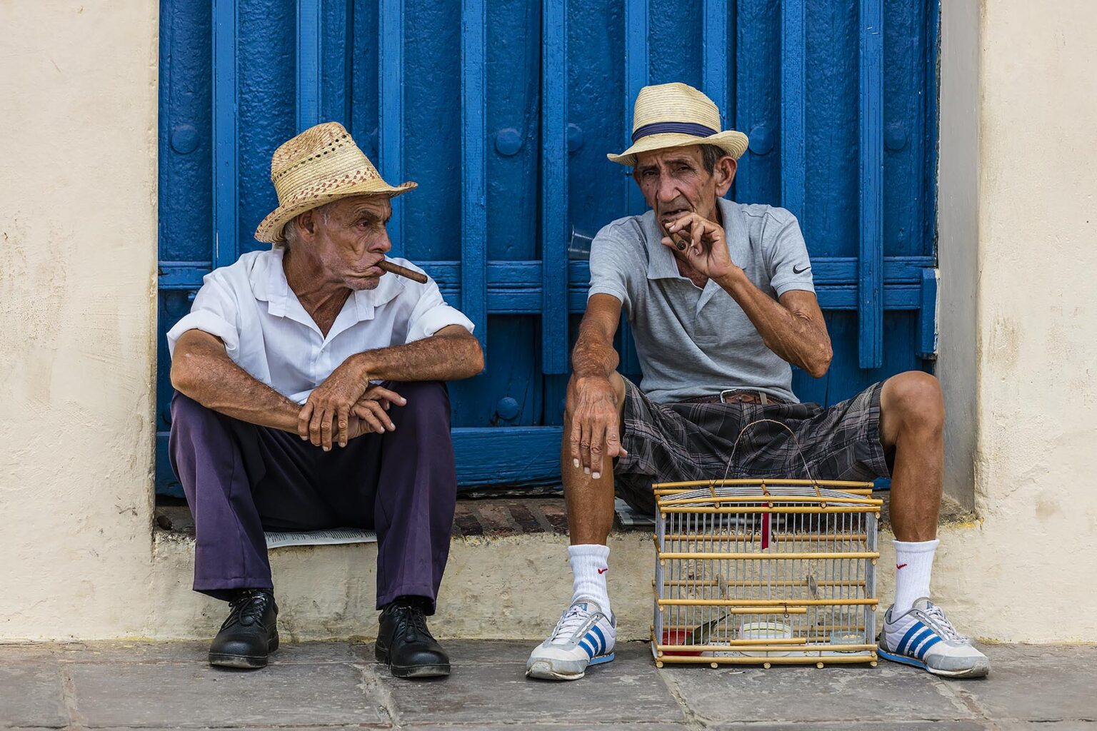 Older Cuban men smoking cigars in the PLAZA MAYOR - TRINIDAD, CUBA