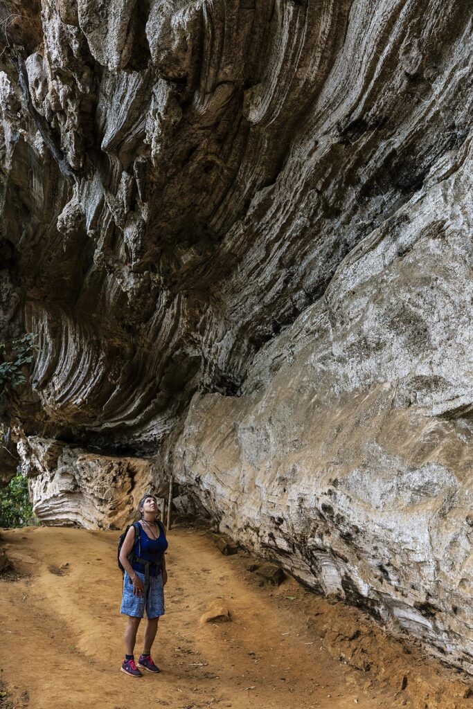 HIKERS under LIMESTONE CLIFF on the trail to SALTO DE CABURNI located the TOPES DE COLLANTES in the mountains of SIERRA DEL ESCAMBRAY - CUBA