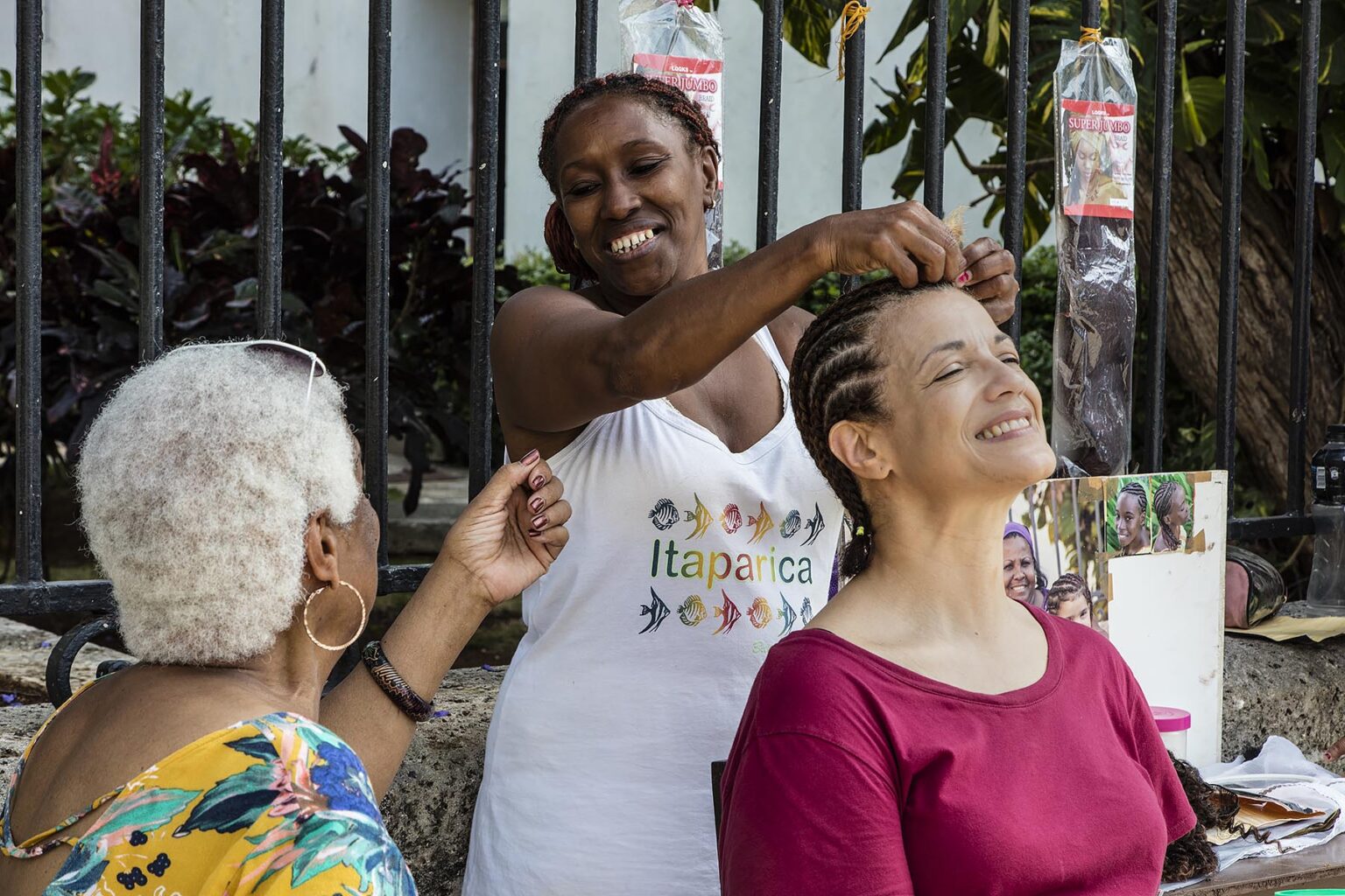 A tourist gets her hair braided in the PLAZA DE ARMAS in HABANA VIEJA - HAVANA CUBA