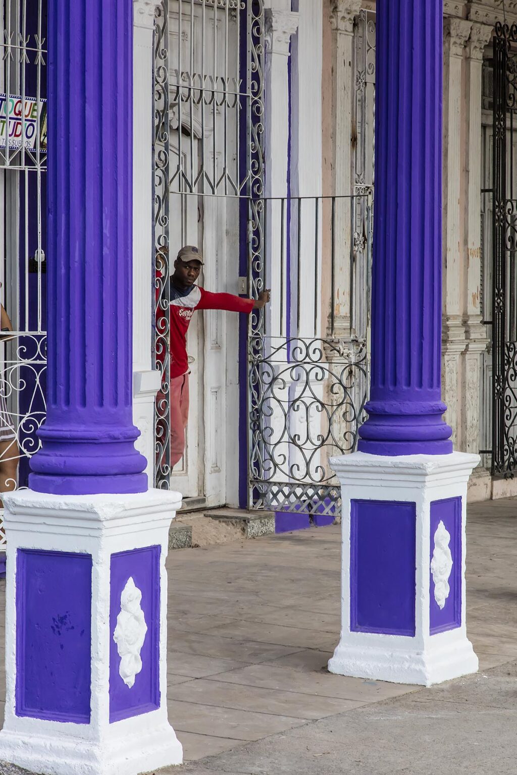 A shop owner between purple pillars - CIENFUEGOS, CUBA