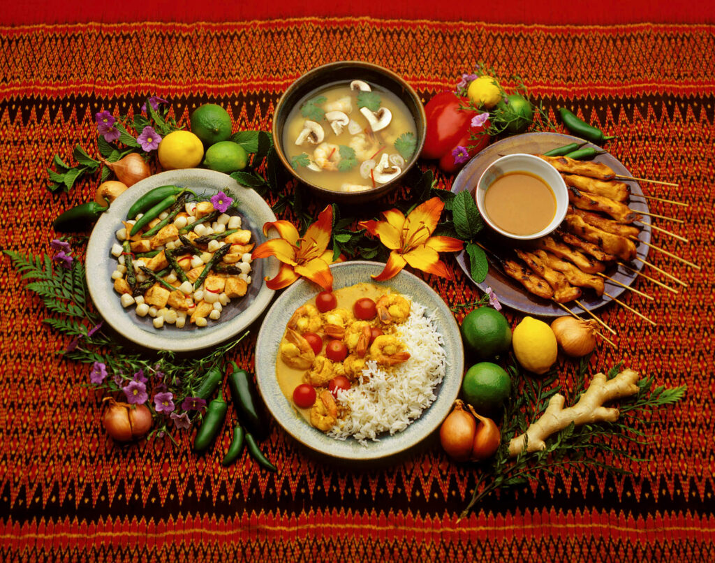 Satay with peanut sauce, curry shrimp, tofu with asparagus and chilis and tom kha ghai or Thai chicken soup are displayed presented before a meal.  Food photograph taken at Eagle Visions Photography studio in Carmel Valley.