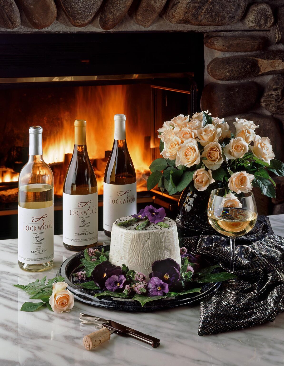 LOCKWOOD VINEYARD WINES with CHEESE and ROSES backlit by warm FIREPLACE