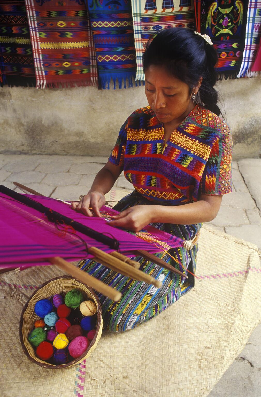 INDIGENOUS WOMAN with traditional BACKSTRAP LOOM weaving a HUIPIL, a traditional brocade cloth - GUATEMALA