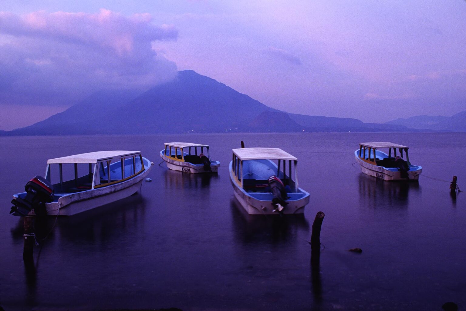 Colorful BOATS docked in PANAJACHEL with VOLCANOS in the distance - LAKE ATITLAN, GUATEMALA
