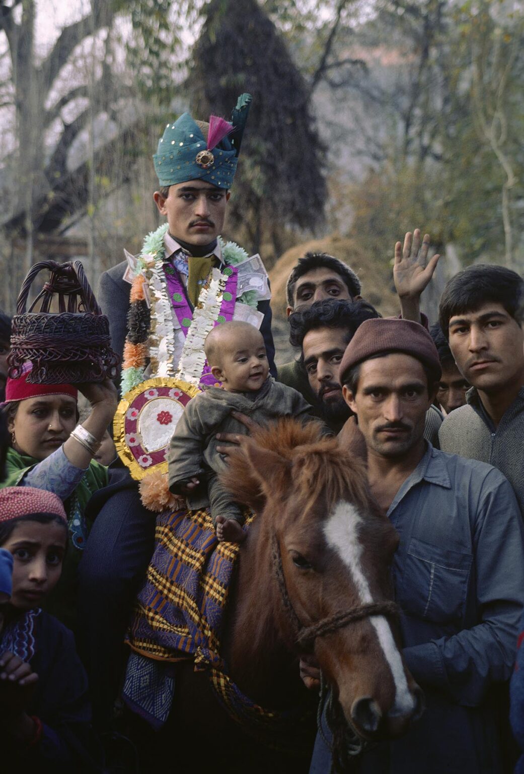 COSTUMED GROOM rides a HORSE to his brides home in AFAN VILLAGE during his WEDDING - KASHMIR, INDIA