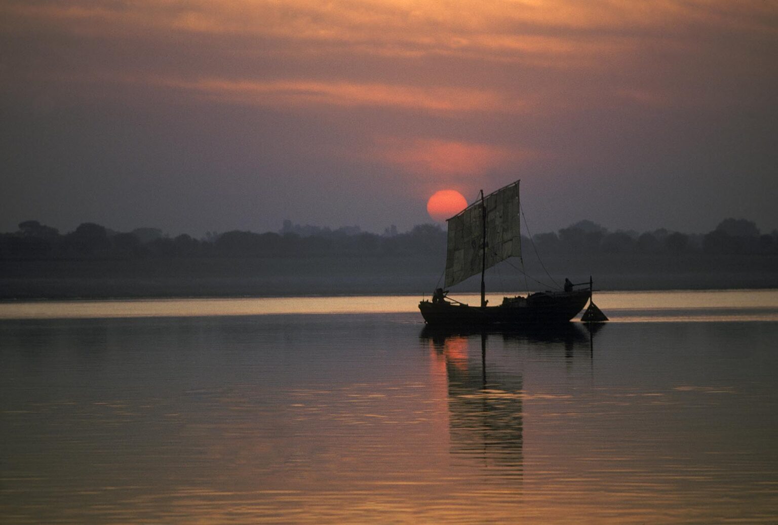 SUNRISE over a small INDIAN fishing boat on the GANGES RIVER - VARANASI (BENARES), INDIA