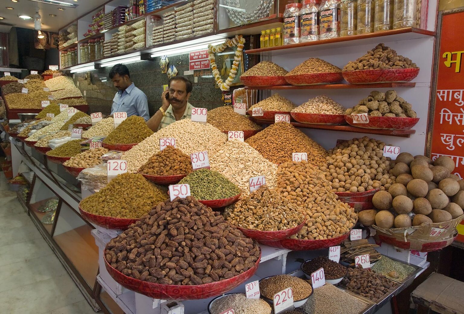 INDIAN MERCHANTS sell spices and dried fruit in the SPICE MARKET of CHANDNI CHOWK OLD DELHI - INDIA