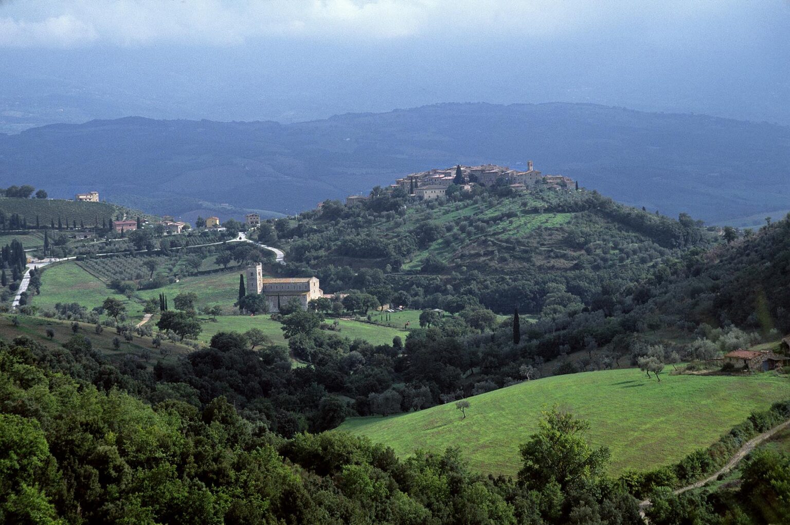 Rolling hills, the Romanesque CHURCH OF SANT' ANTIMO and the town of CASTELNUOVO DELL' ABATE - TUSCANY, ITALY