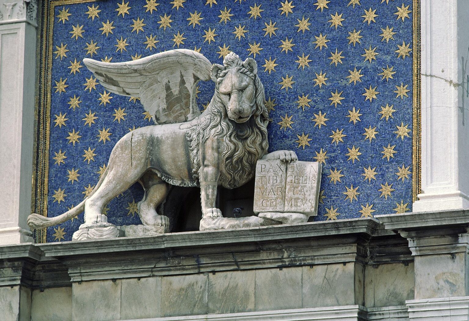 A stone LION WITH WINGS sits above the Astronomical Clock in the main plaza of VENICE - ITALY