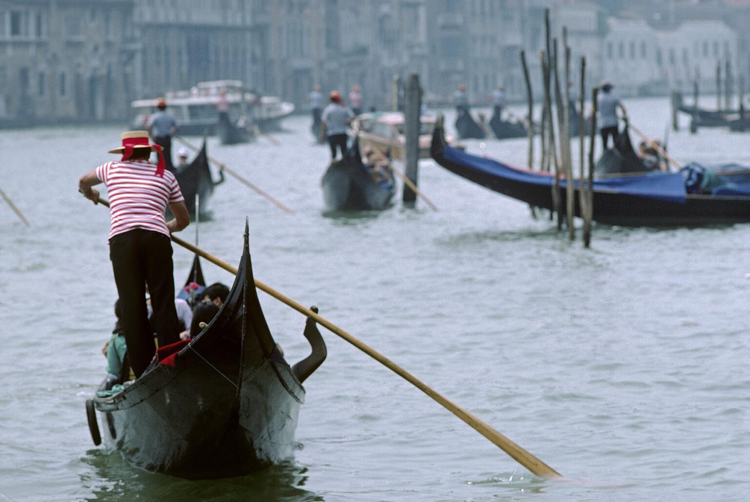 A GONDOLA CAPTAIN steers his vessel through the canals of VENICE - ITALY