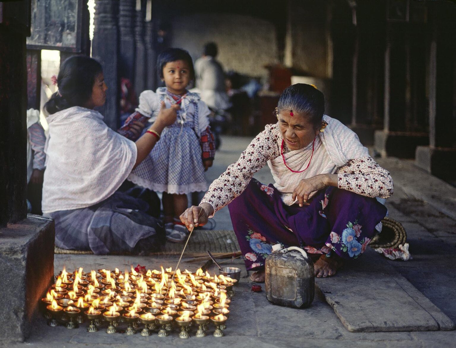 A NEWARI woman lights PUJA CANDLES at SWAYAMBUNATH STUPA - KATHAMANDU, NEPAL