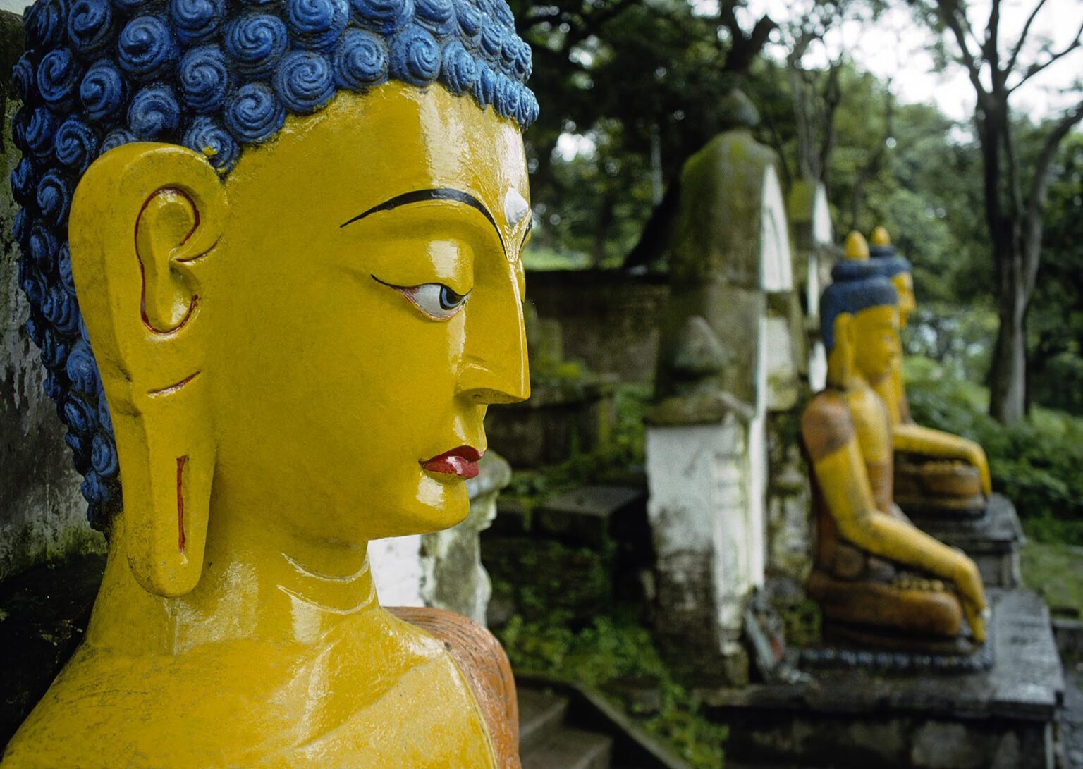 Statues of SAKYAMUNI BHUDDA an the steps up to SWAYAMBUNATH STUPA - KATHAMANDU, NEPAL