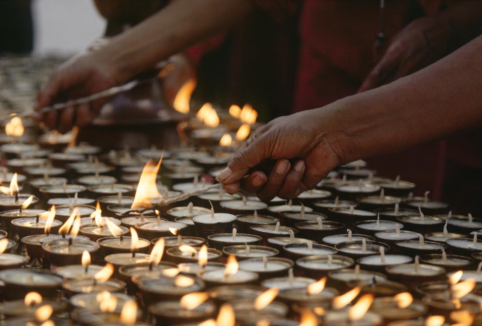 Buddhist Monks light PUJA CANDLES at BODHANATH STUPA - KATHAMANDU, NEPAL