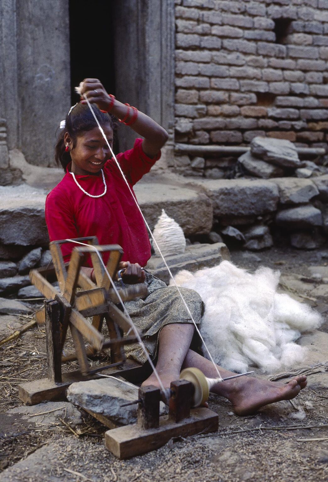Newari girl spins wool into thread - Bhaktapur, Nepal