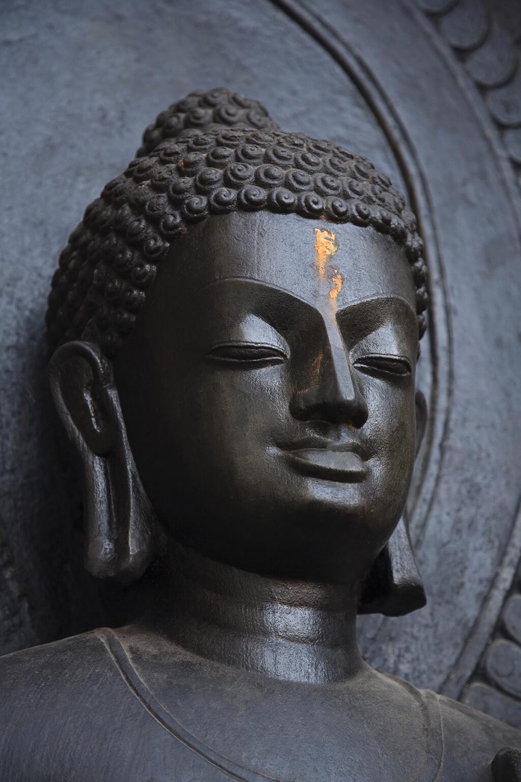An ancient STONE CARVED SAKYAMUNI BUDDHA statue at the SWAYAMBHUNATH TEMPLE COMPLEX - KATHAMANDU, NEPAL