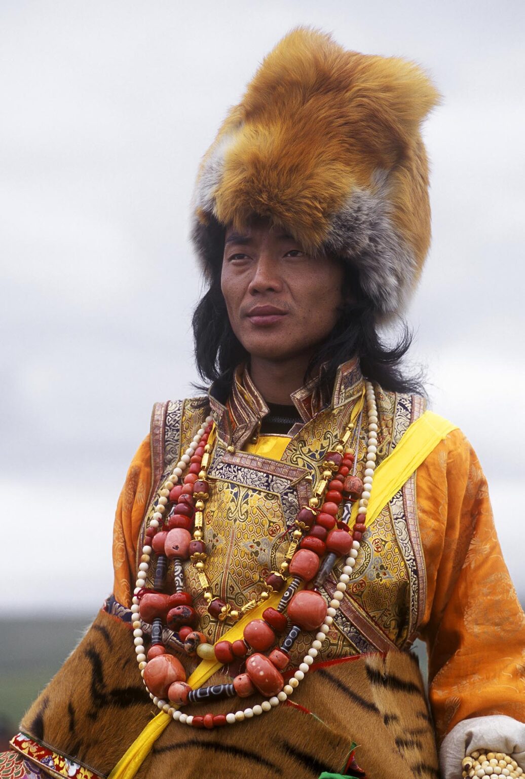 Male Khampa wears coral, zee stones, fox fur hat and tiger skin at the Litang Horse Festival - Sichuan Province, China, (Tibet)