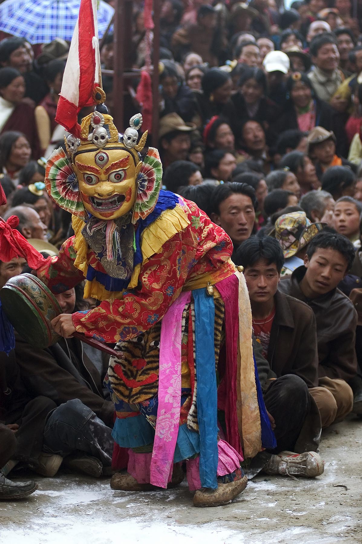 Masked dancer sits on crowd as part of the performance at the Monlam Chenmo, Katok Monastery - Kham, (Tibet), Sichuan, China