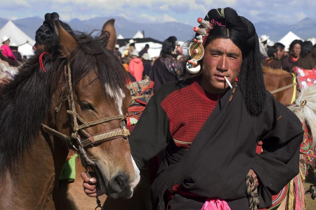 Khampa man and Tibetan pony wait for a chance to race at the Litang Horse Festival - Kham, Sichuan Province, China, (Tibet)