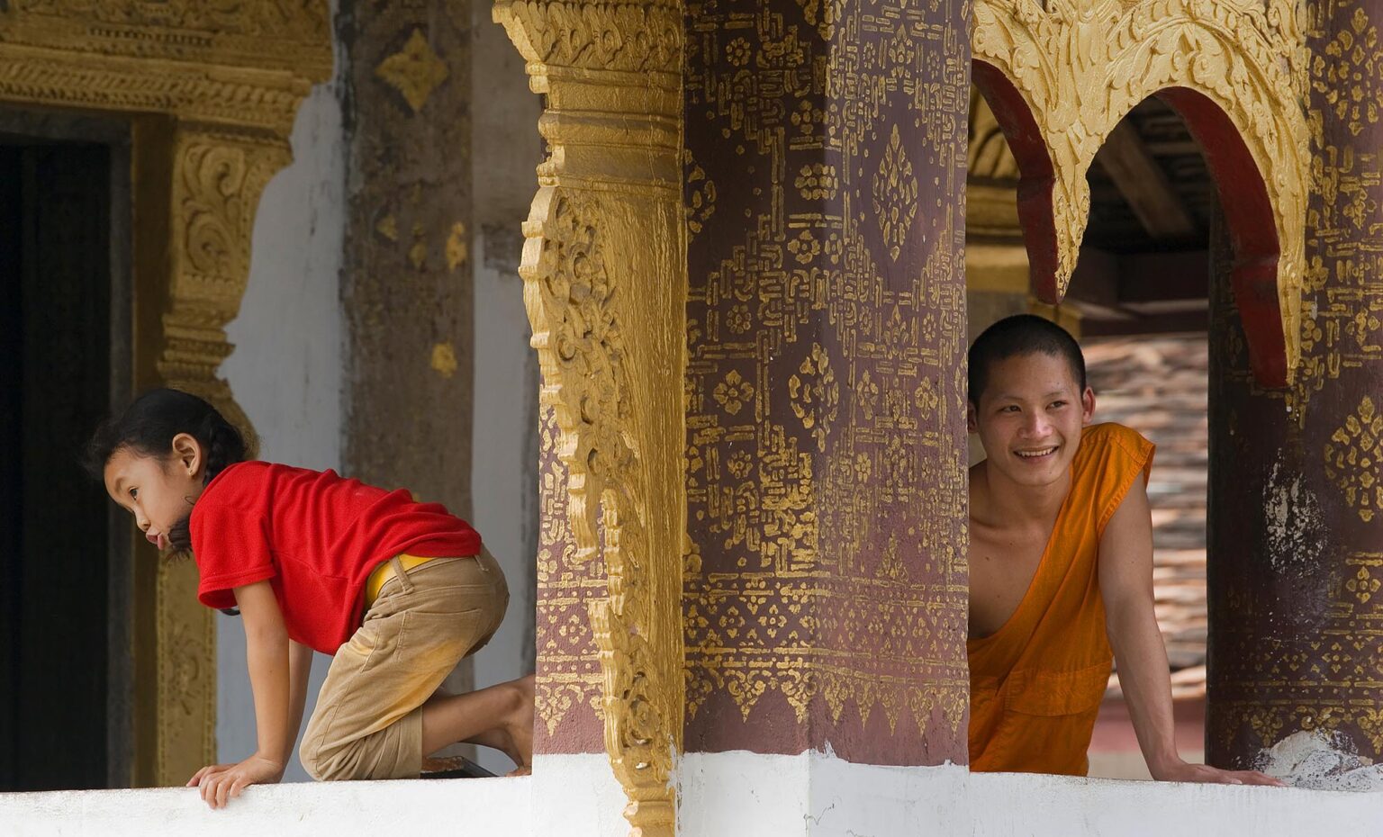 Hinayana Buddhist monk & Laotian girl at Wat Si Bun Heuang in the former French Provincial town of LUANG PROBANG - LAOS