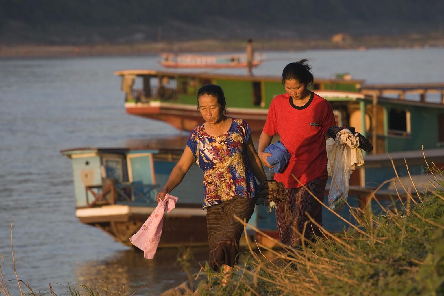Laotian women walk along the banks of the Mekong River in LUANG PROBANG - LAOS