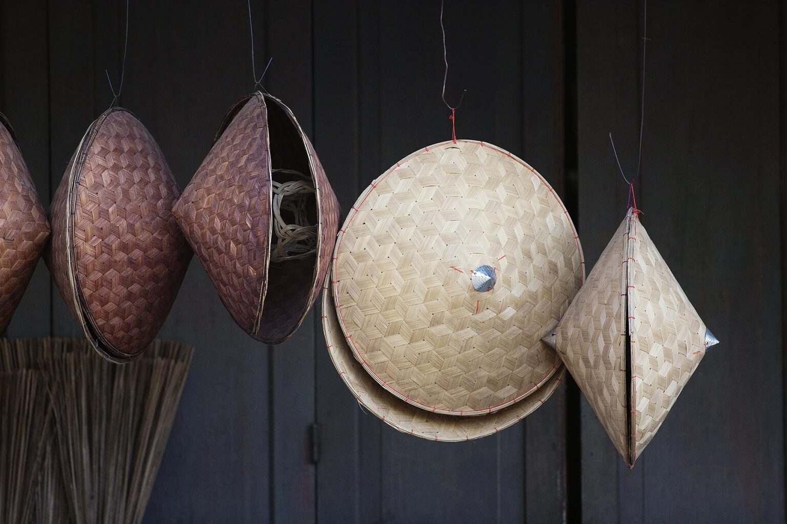 Hand woven rattan hats hang in a shop - LUANG PROBANG, LAOS