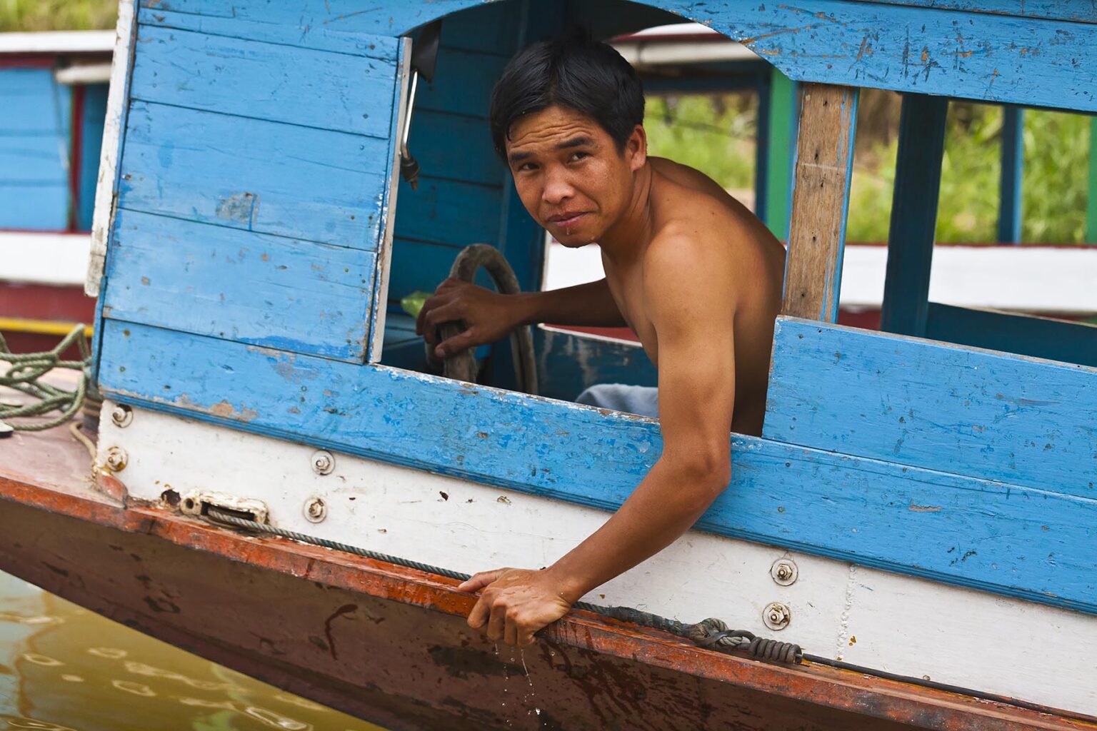 LAOTIAN man drives a boat on the MEKONG RIVER- LUANG PRABANG, LAOS