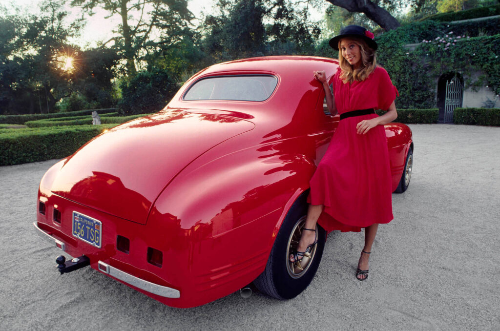 A fashionable young woman poses with a customized classic American car.  Commercial photography by Craig Lovell