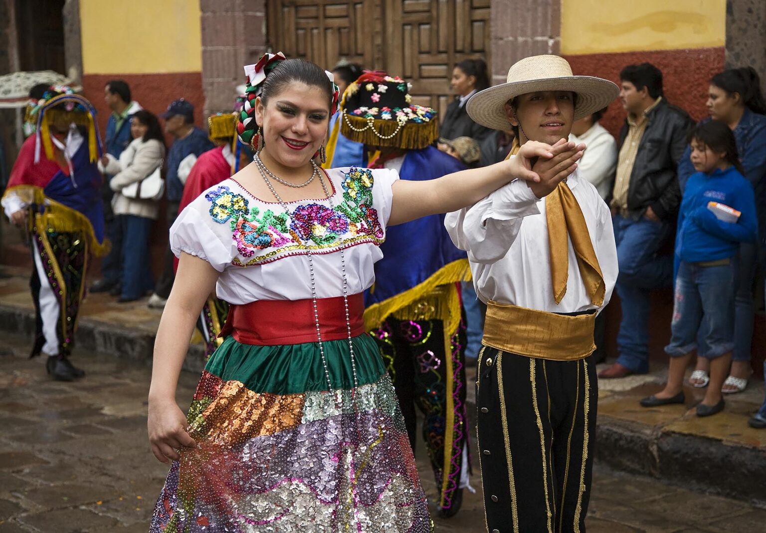 A MEXICAN couple in traditional PEASANT COSTUME walks in the FESTIVAL DE SAN MIGUEL ARCHANGEL PARADE - SAN MIGUEL DE ALLENDE, MEXICO