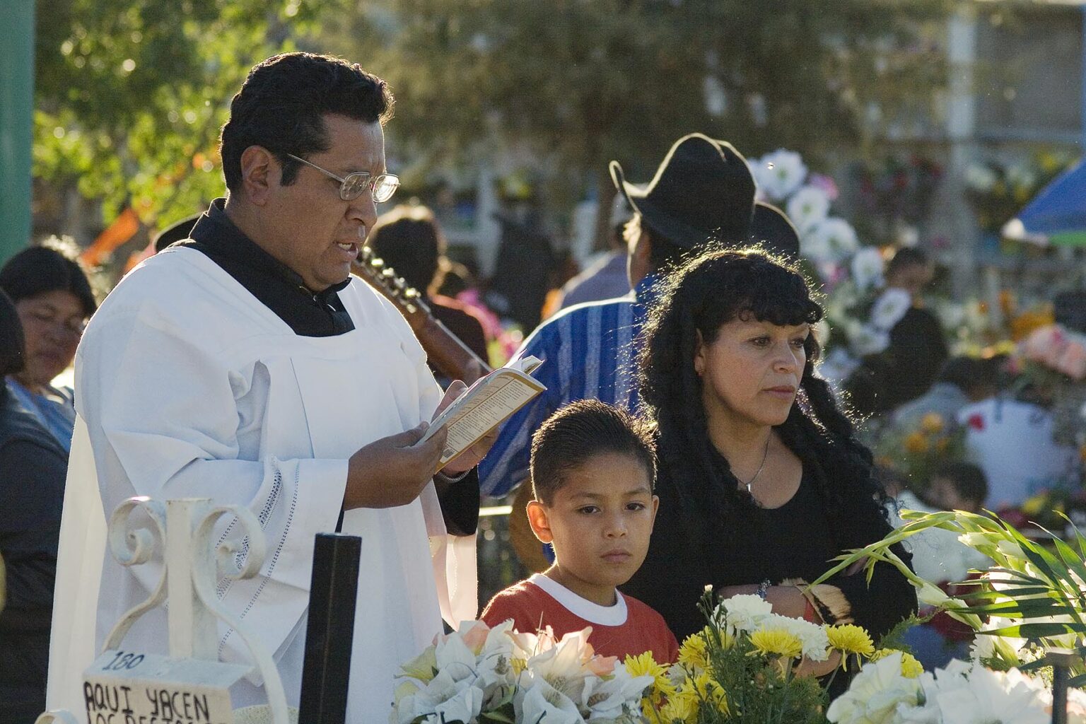 A PRIEST says prayers over a grave during the DEAD OF THE DEAD - SAN MIGUEL DE ALLENDE, MEXICO