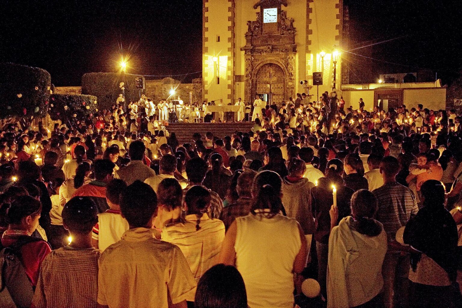 Devout CATHOLICS light candles during EASTER MASS at SAN ANTONIO CHURCH - SAN MIGUEL DE ALLENDE, MEXICO