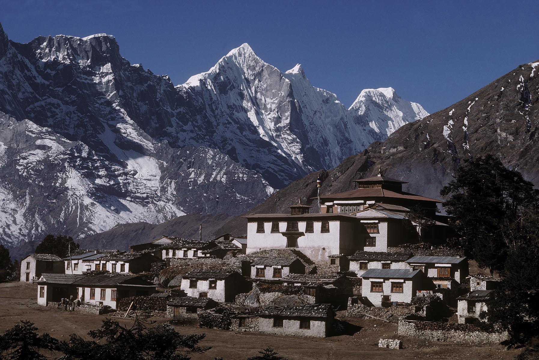 Himalayan peaks tower behind houses in the village of Tengboche, Khumbu, Nepal.