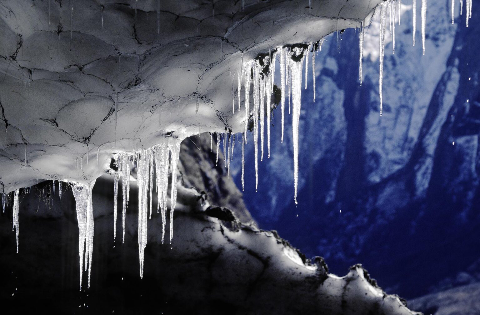 Sunlight illuminates WATER DRIPPING from ICICLES on the ceiling of a SNOW CAVE - ANNAPURNA SANCTUARY, NEPAL