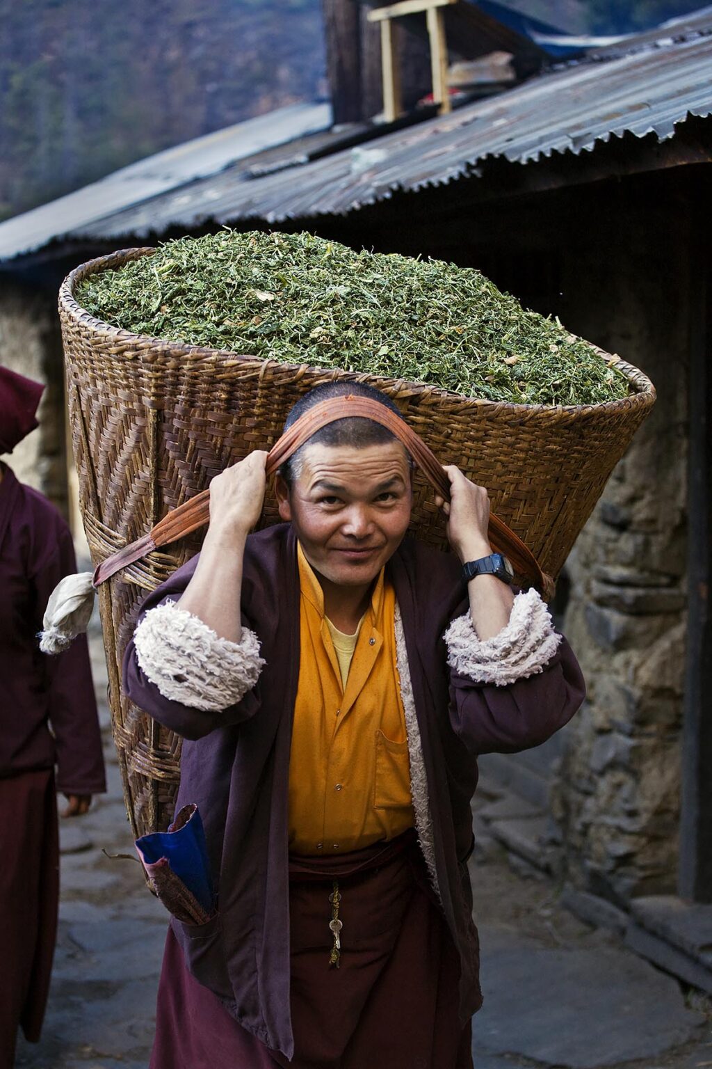 A monk carries a DOLKO or basket of animal feed at a remote TIBETAN BUDDHIST MONASTERY - NEPAL