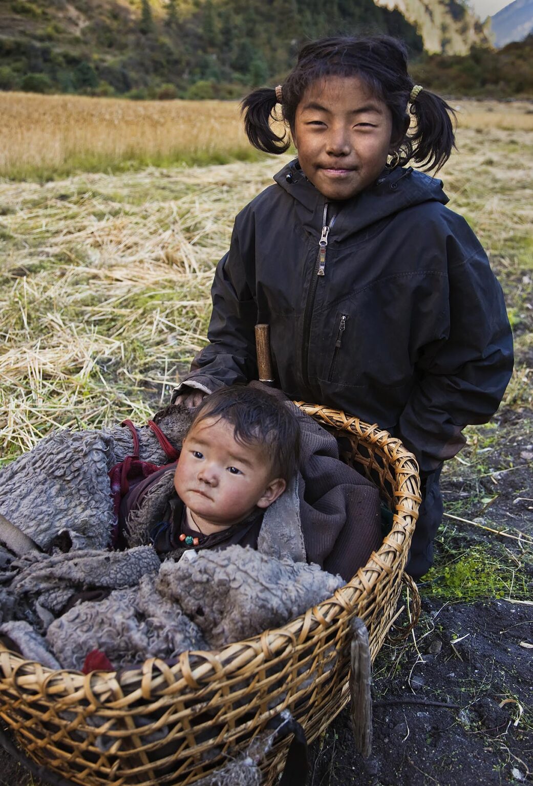 A NEPALI baby a basket with her older sister in NUPRI - AROUND MANASLU TREK, NEPAL