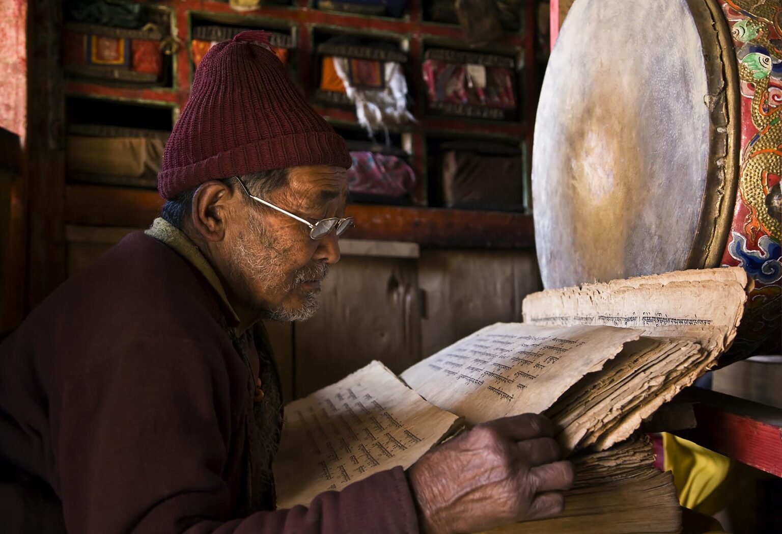 A TIBETAN BUDDHIST MONK reads SACRED TEXTS in the village of SAMDO on the AROUND MANASLU TREK - NUPRI REGION, NEPAL