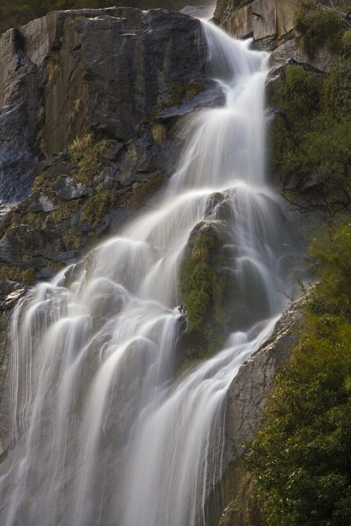 A WATERFALL drops off the steep cliffs on the AROUND ANNAPURNA TREK - NUPRI REGION, NEPAL