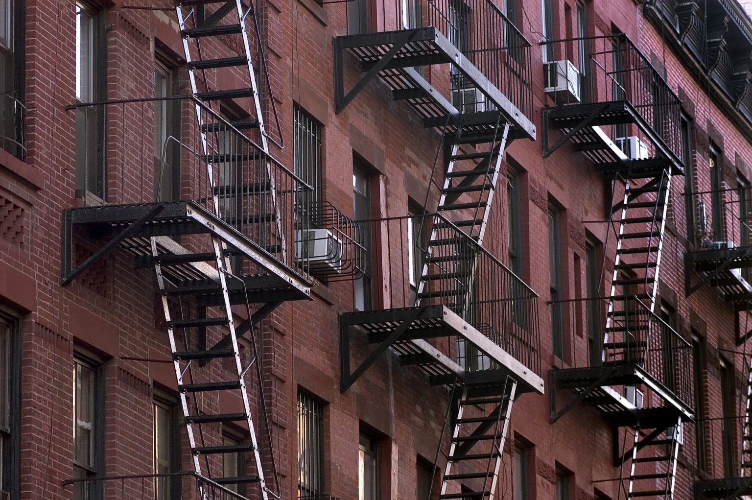 RED BRICK BUILDING and BLACK METAL FIRE FIRE ESCAPE STAIRS n MANHATTAN - NEW YORK CITY, NEW YORK, USA