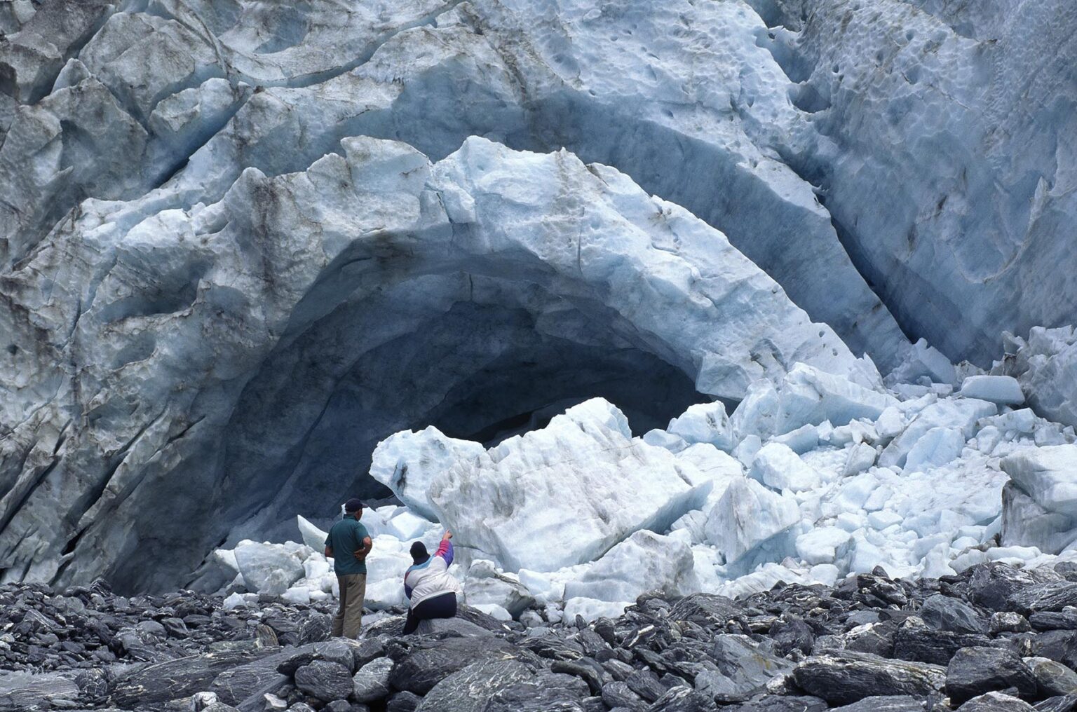 Visitors explore the mouth of the FRANZ JOSEF glacier - SOUTH ISLAND, NEW ZEALAND