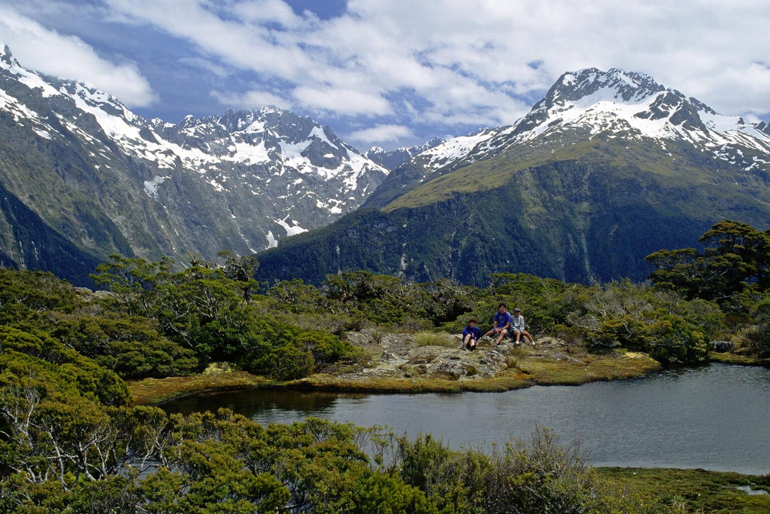 Trekkers rest on KEY SUMMIT with MT CHRISTINA & MT CROSSCUT (R) as backdrop - FIORDLAND NATIONAL PARK, NEW ZEALAND'S SOUTHLAND