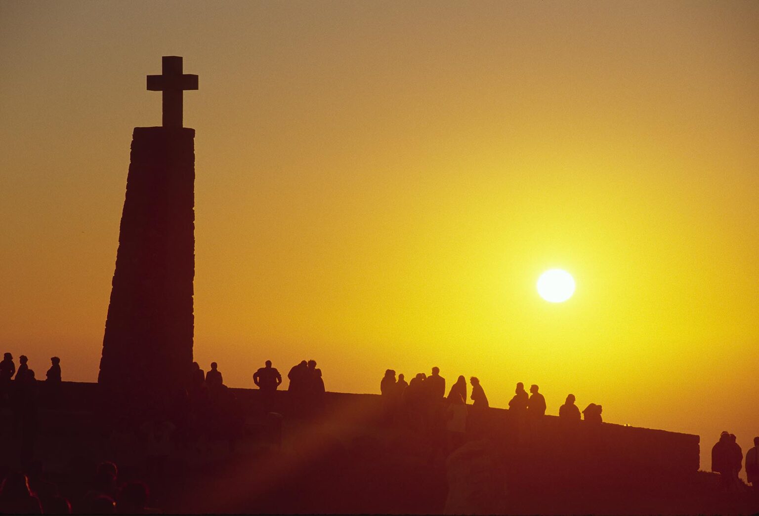 People watch the sunset below a giant cross at CABO DE ROCA, EUROPE'S most western point near LISBON - PORTUGAL