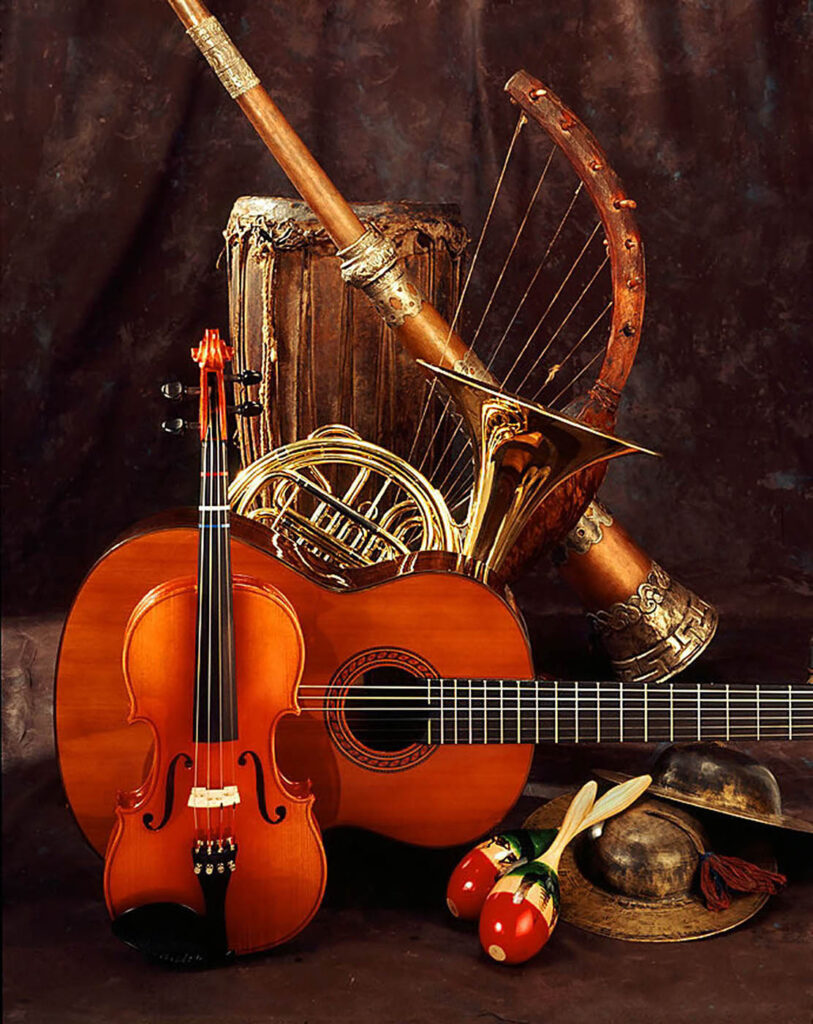 Still-life of musical instruments including guitar, violin, maracas, African drum, Tibet horn and cymbals.  Commercial studio shot by Craig Lovell.