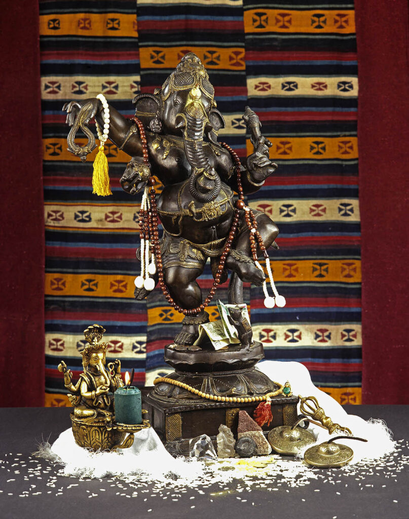 BRONZE CASTINGS of the HINDU/BUDDHIST DIETY GANESH (Elephant God) with MALLAS, TINKSHAS, CANDLES and CRYSTALS. Commercial studio shot by Craig Lovell.