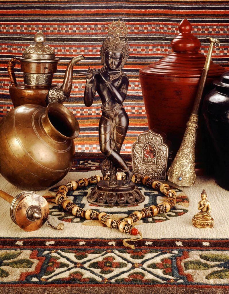 ASIAN ARTIFACTS and RITUAL OBJECTS with KRISHNA STATUE, TIBETAN PRAYER WHEEL, GAU BOX, TIBETAN HORN AND traditional TEA POT.  Still-life by Craig Lovell.